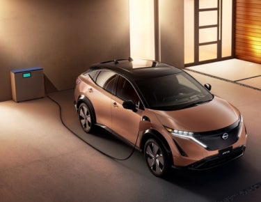 Nissan ARIYA plugged-in and charging outside a home | Banister Nissan of Norfolk in Norfolk VA