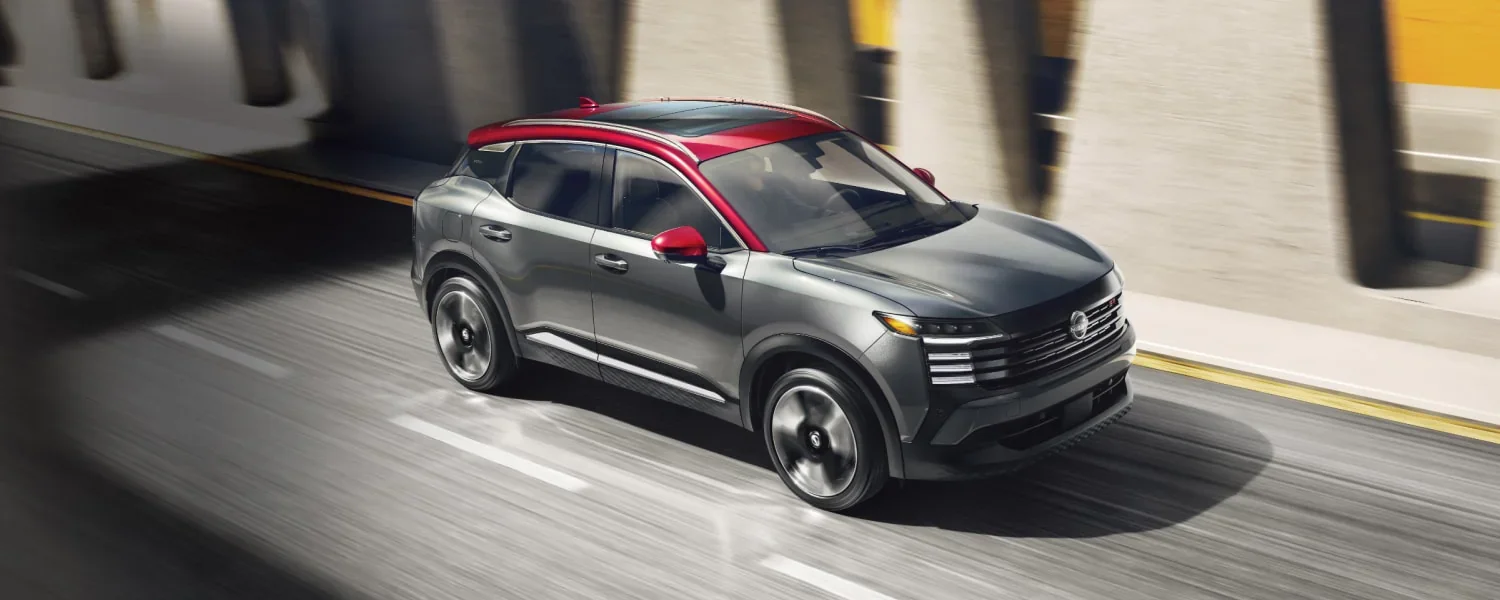 black and red nissan kicks driving on a road through town