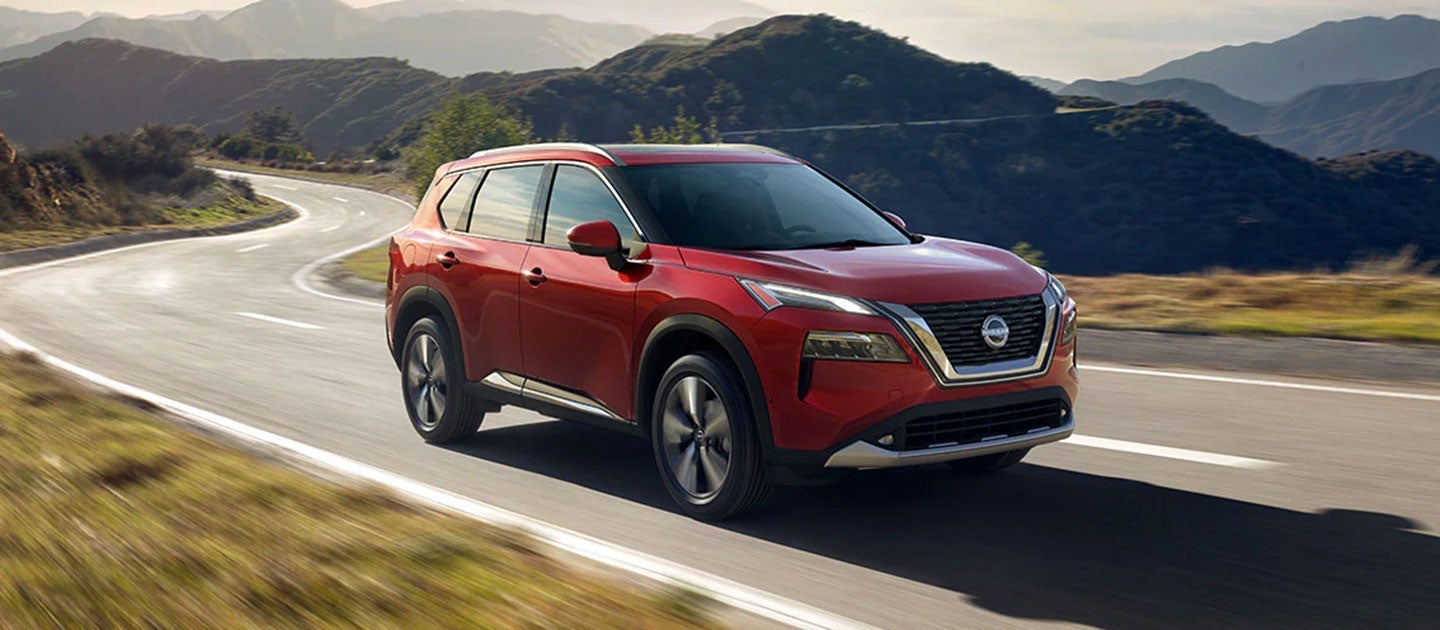 red nisan rogue driving down a curvy road
